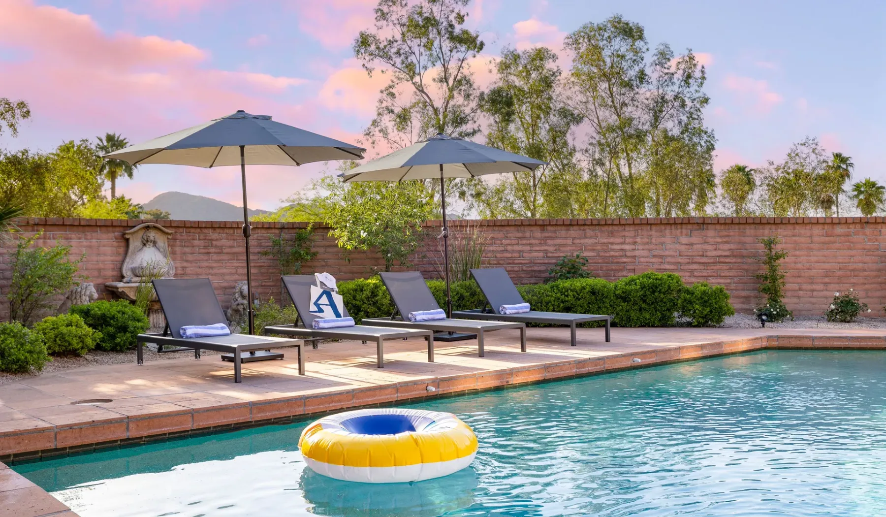 Una piscina al aire libre con asientos reclinables y sombrillas al lado.