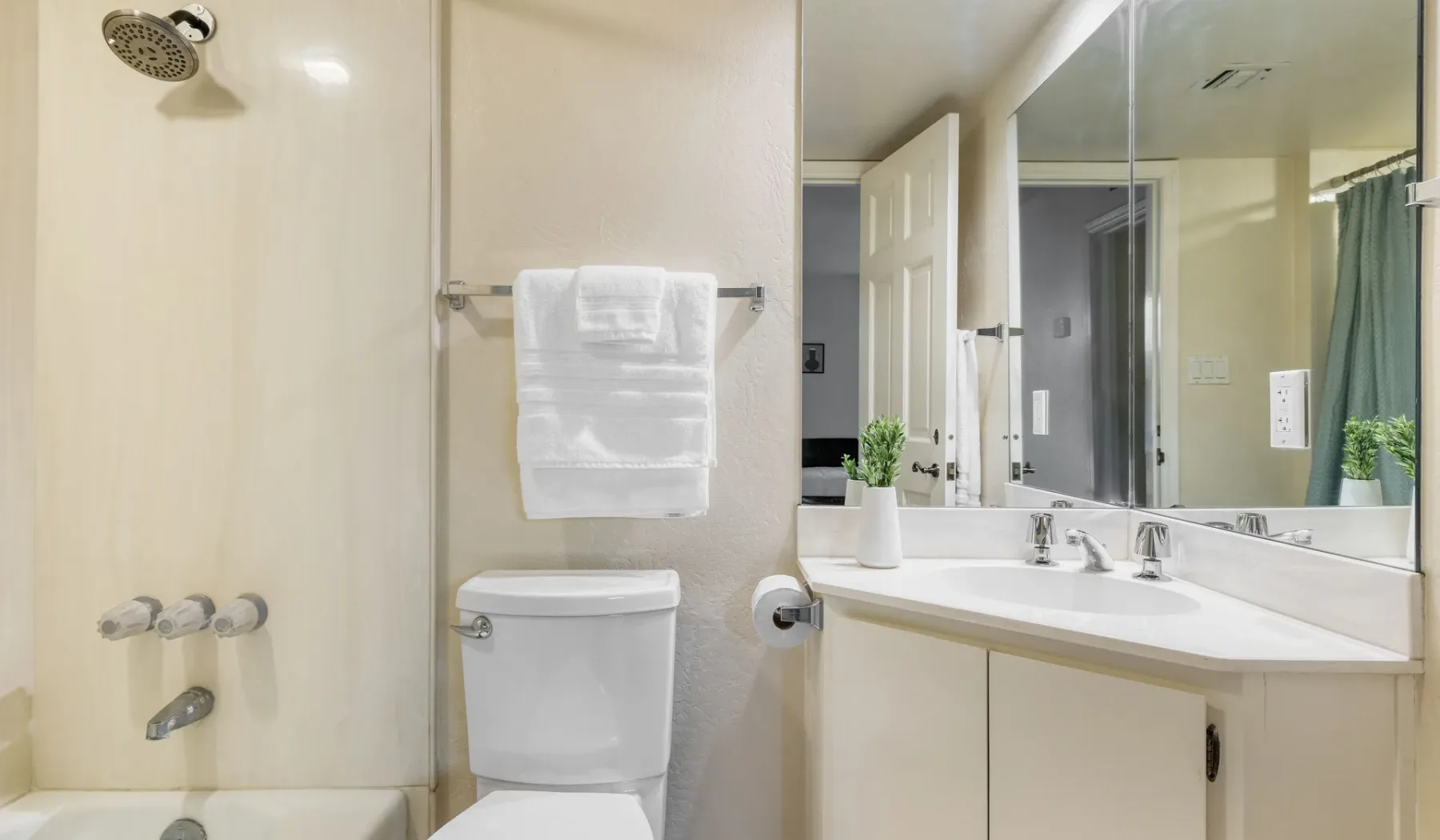 Un baño con ducha, inodoro y lavabo bajo un espejo grande.