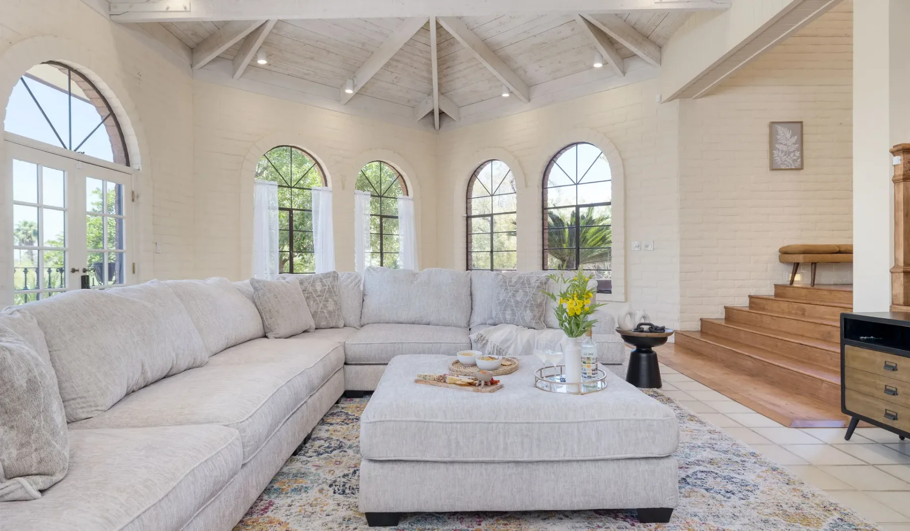 Una sala luminosa con un área de asientos y altas ventanas arqueadas.