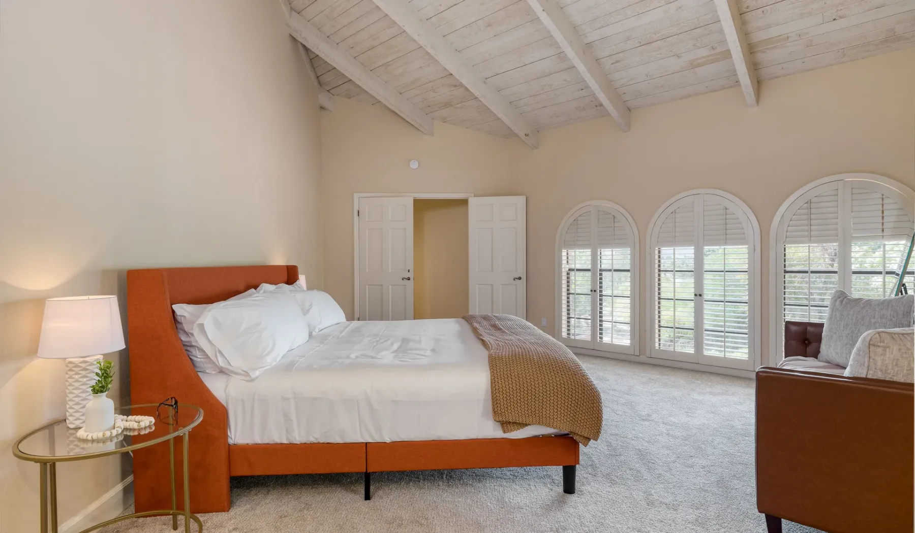 Un dormitorio con una cama y ventanas altas en arco.
