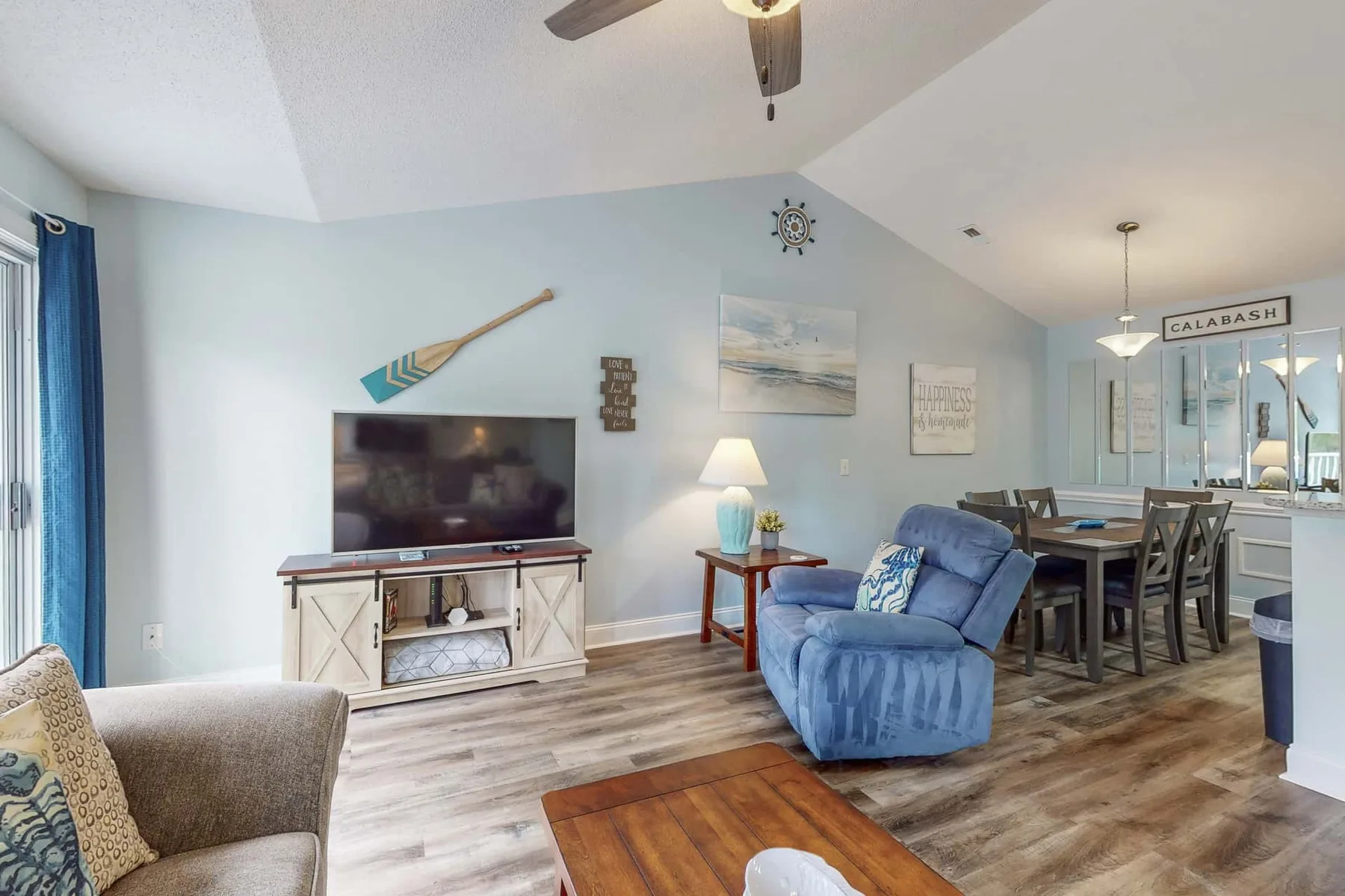 A living room with blue seating, a television, and a dining table.