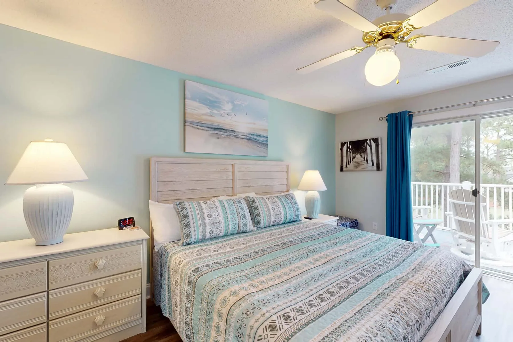 A bedroom with a bed, bedside lamps, and a glass door opening to a balcony.