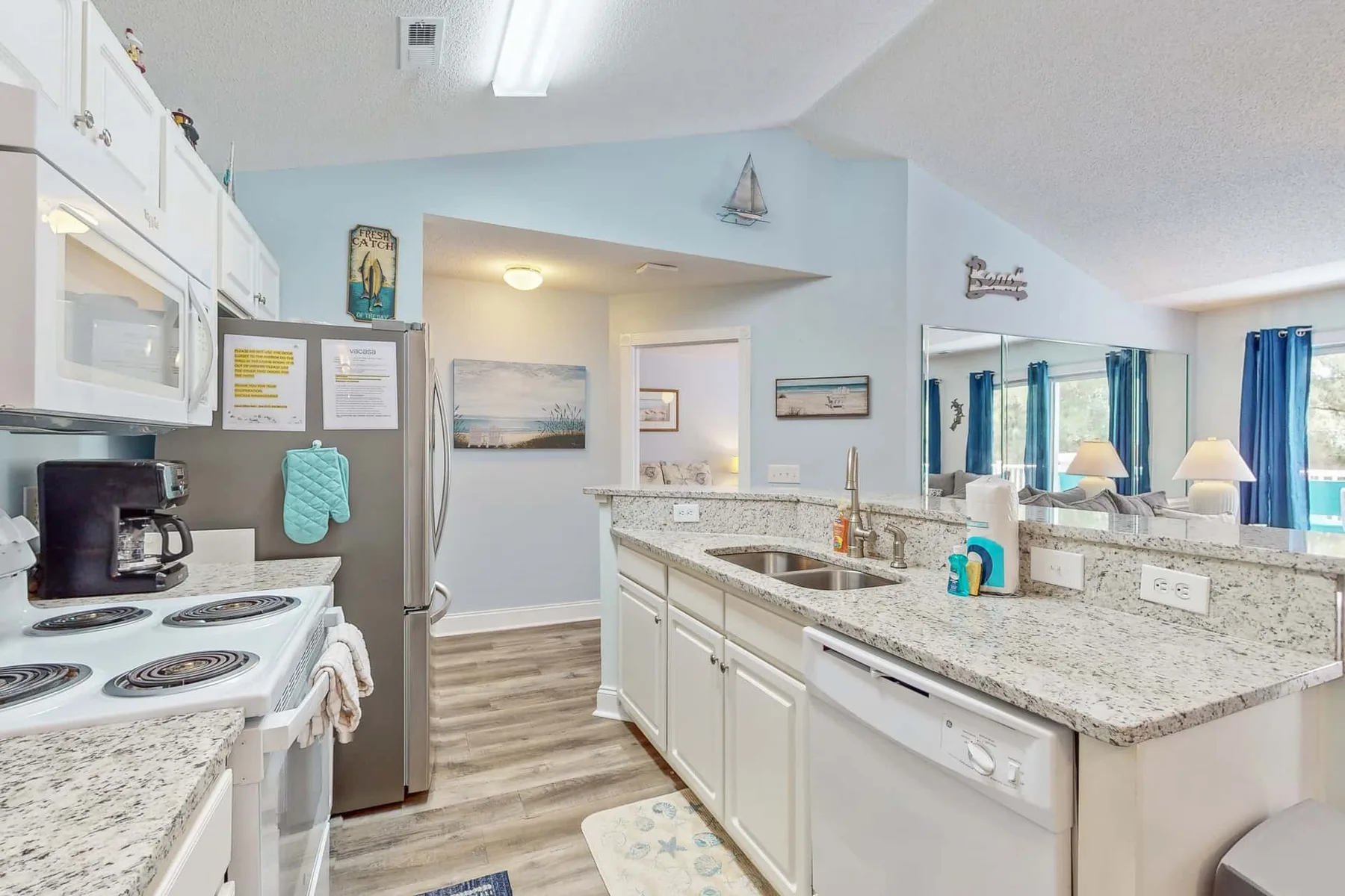 A bright kitchen with white cabinets, a stove, and a central countertop.