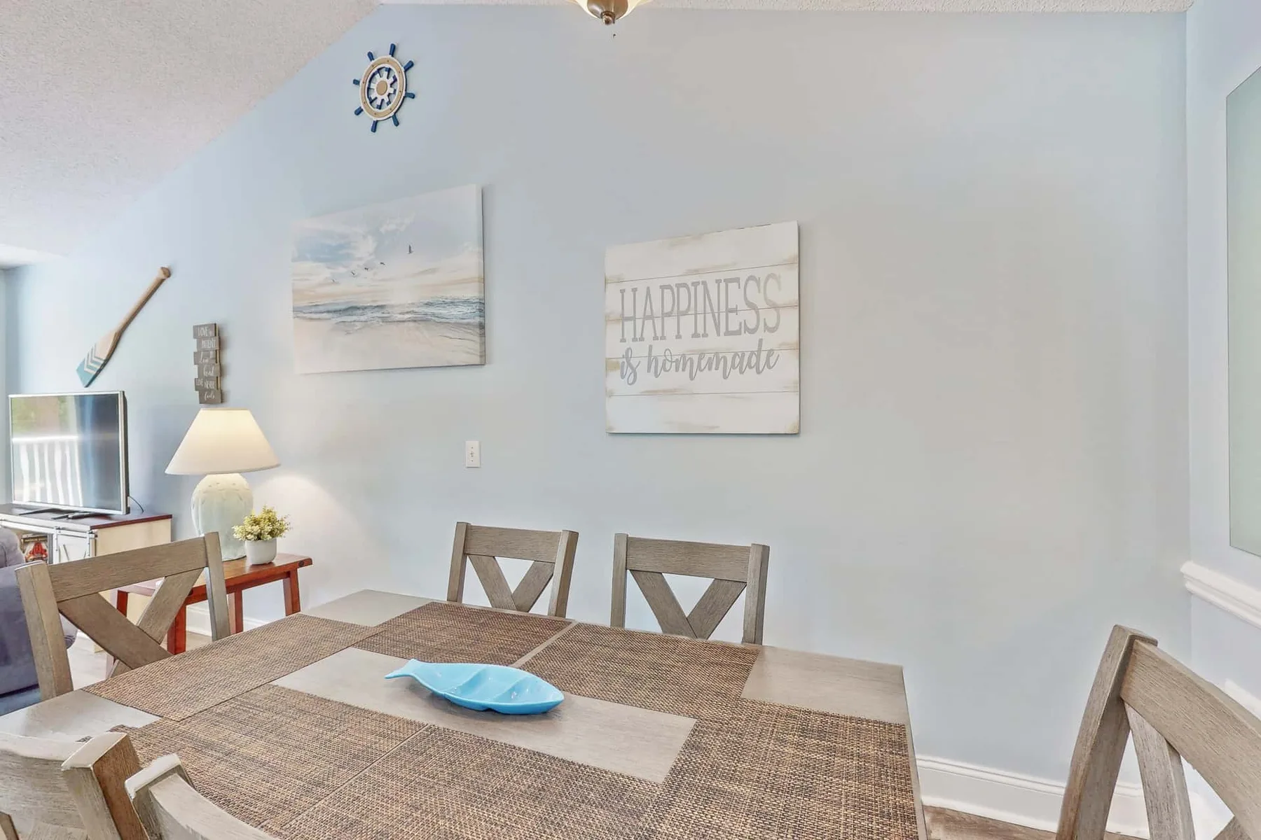 A dining area with a wooden table, chairs, and wall art.