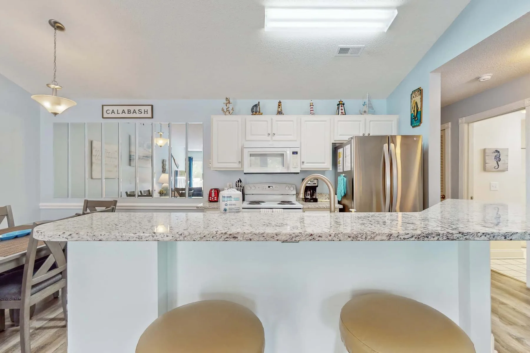 A bright kitchen with a wide island and stainless steel appliances.