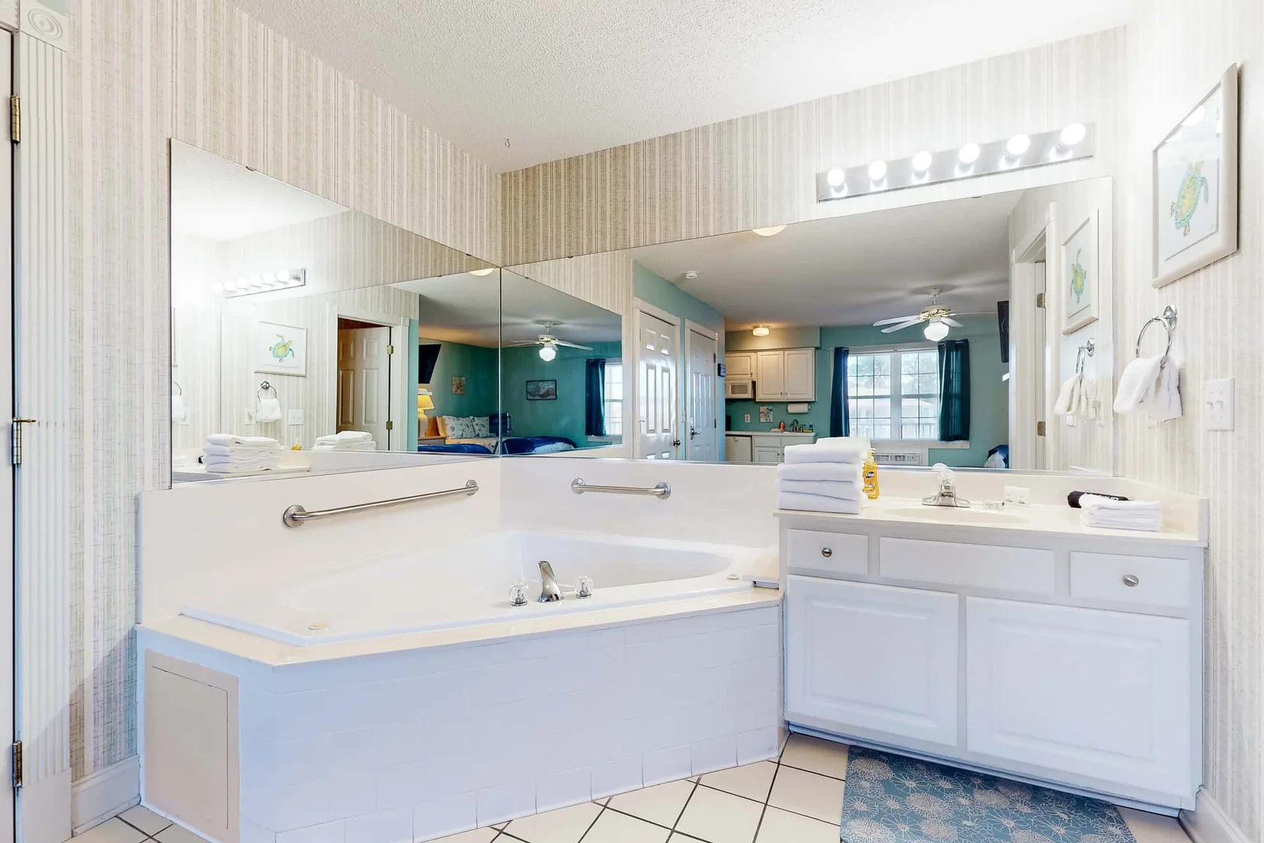 A bright bathroom with a large bathtub, vanity, and broad mirrors.