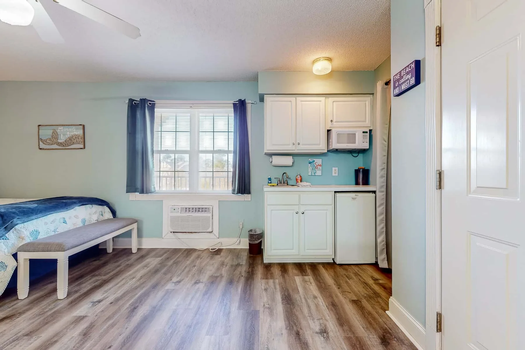 A compact room combines sleeping space with a small kitchenette and a window.