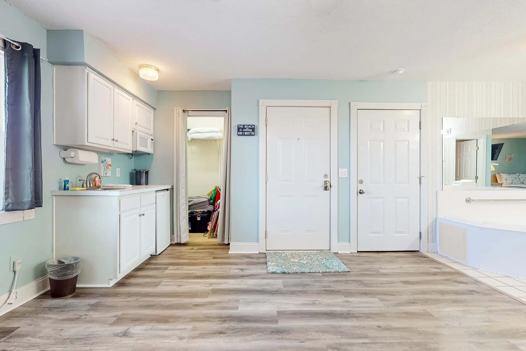 A bright room with white cabinets, two doors, and a small rug.