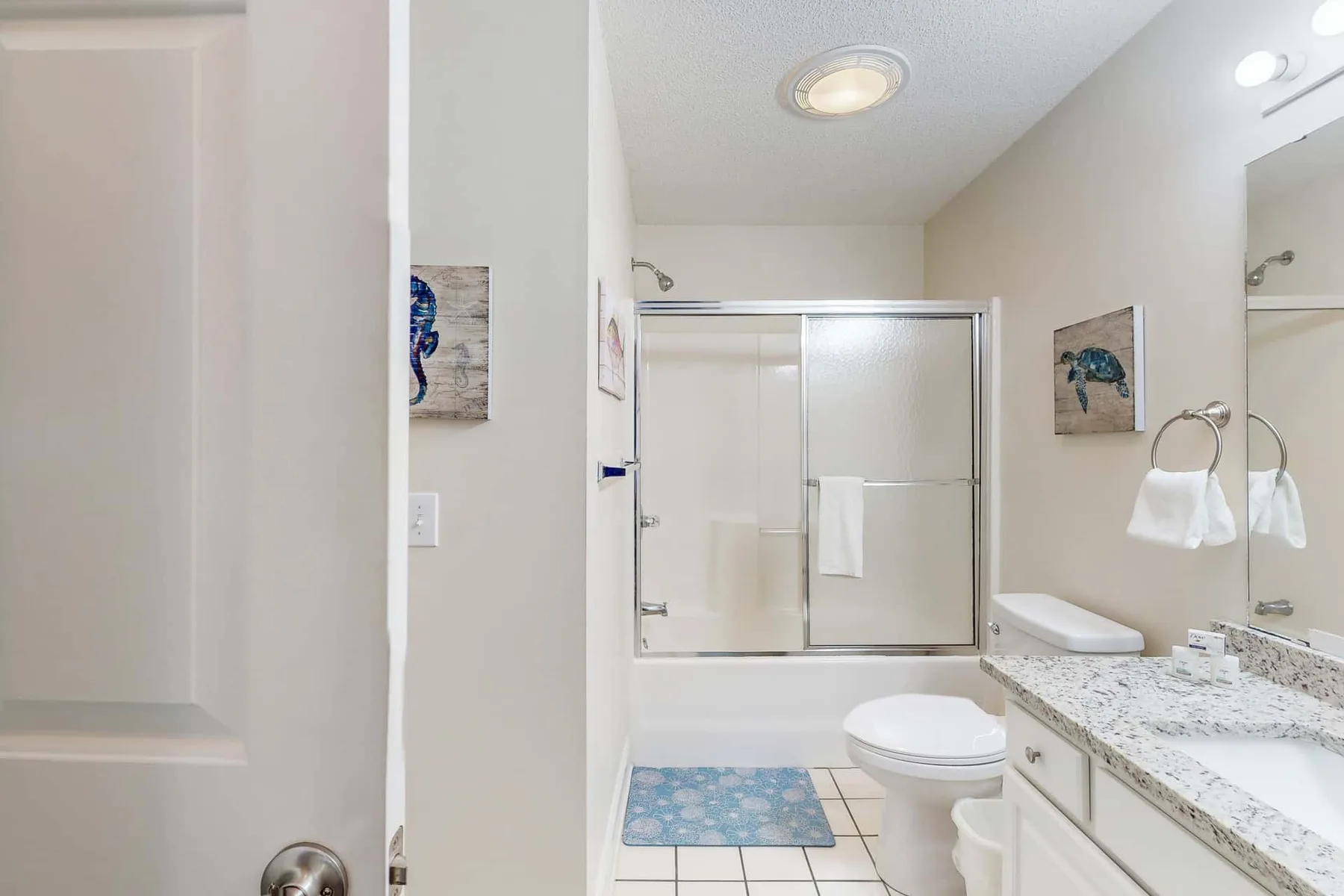 A bathroom with a glass shower, toilet, and vanity.