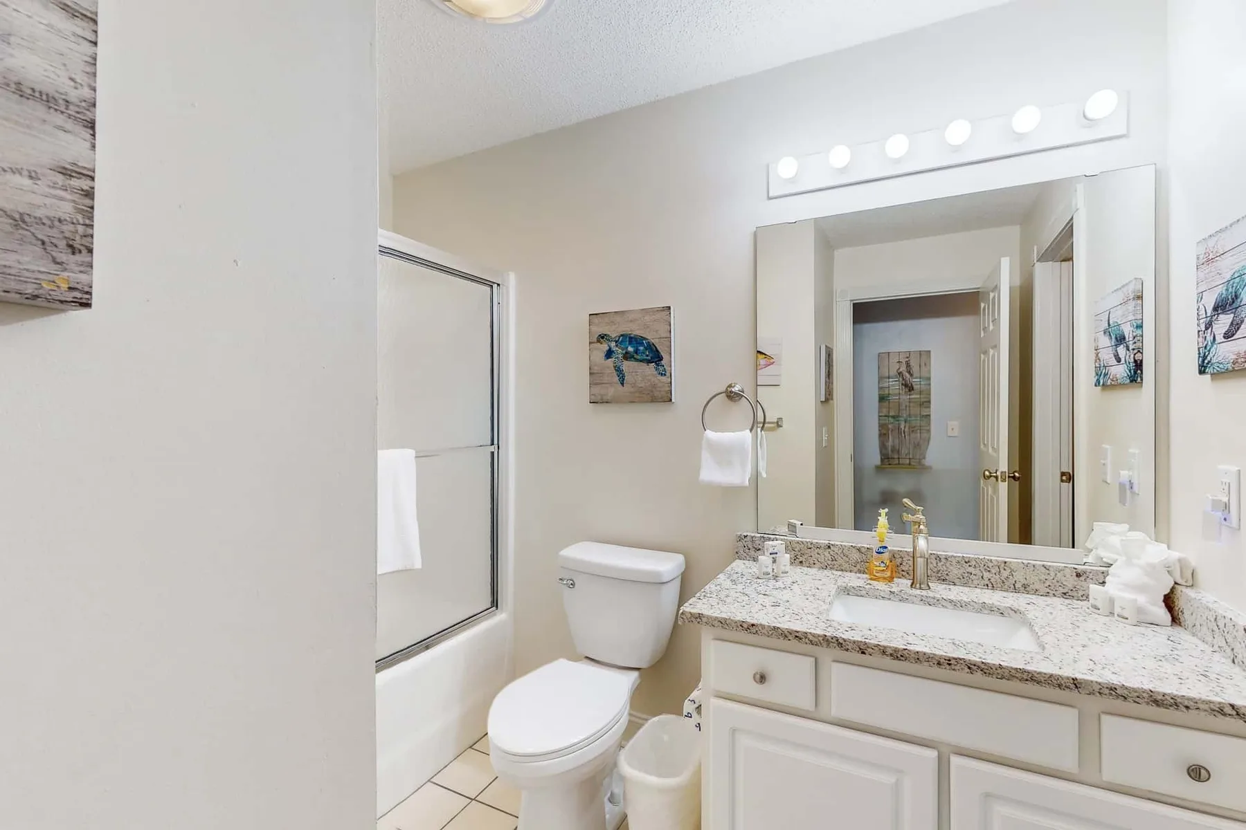 A bright bathroom with a bathtub, toilet, and wide vanity.