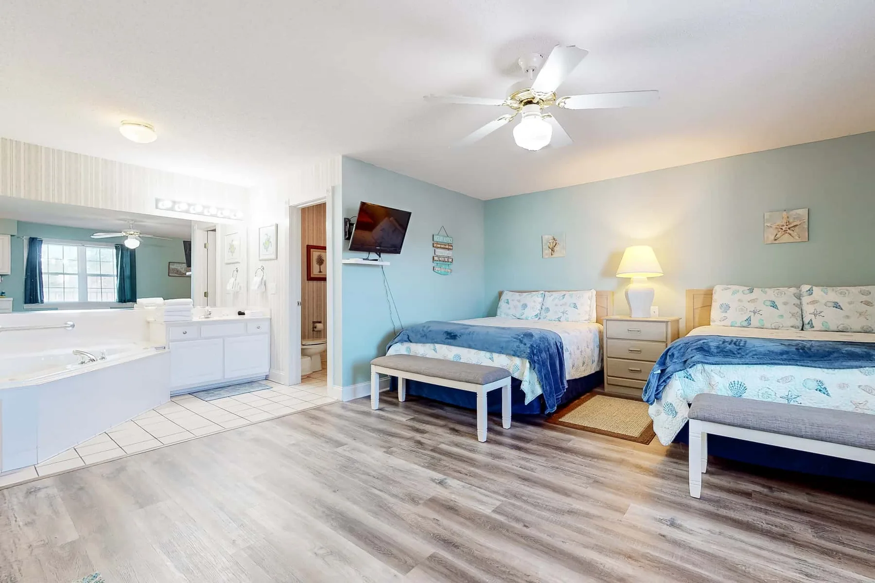 A bedroom with two beds and an adjoining vanity area.