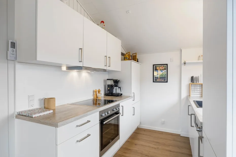 A bright kitchen with white cabinetry, a countertop, and wood flooring.