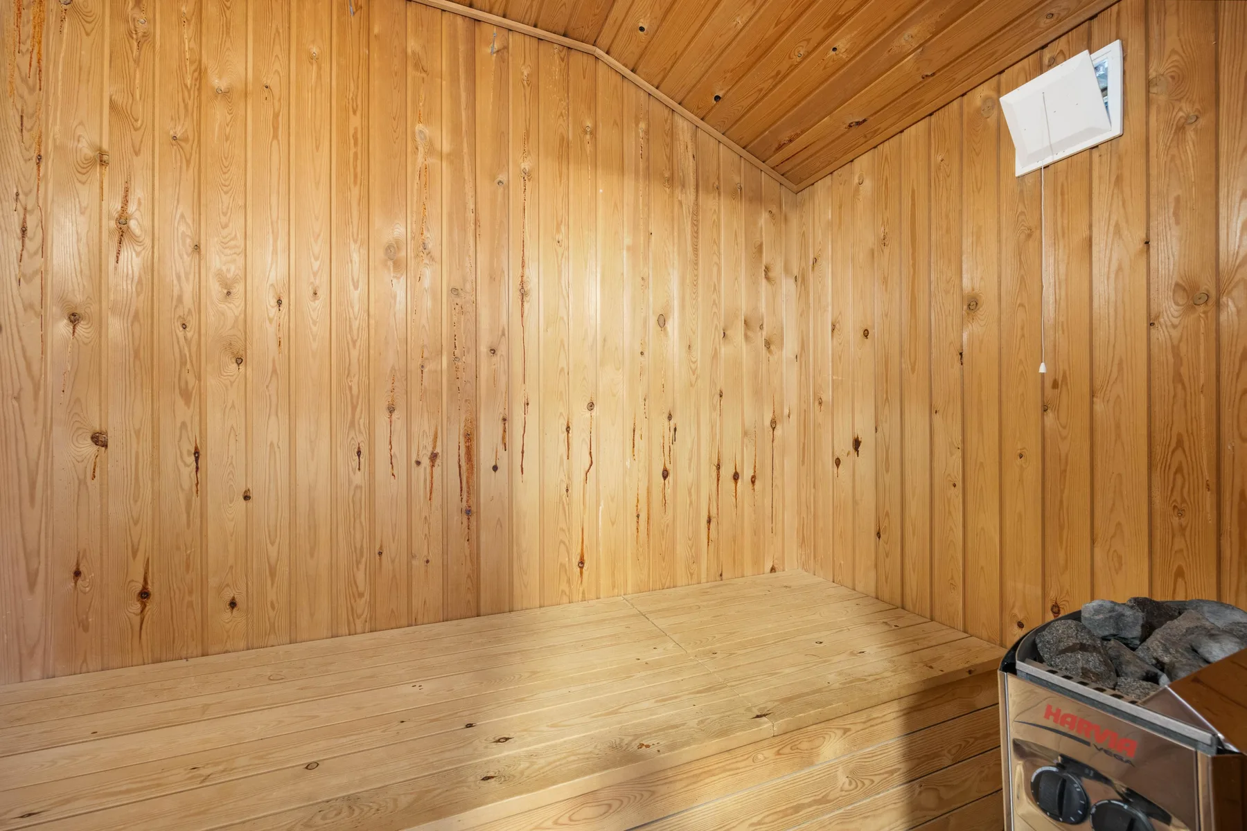 A wood-paneled sauna with a raised wooden bench and a heater in the corner.