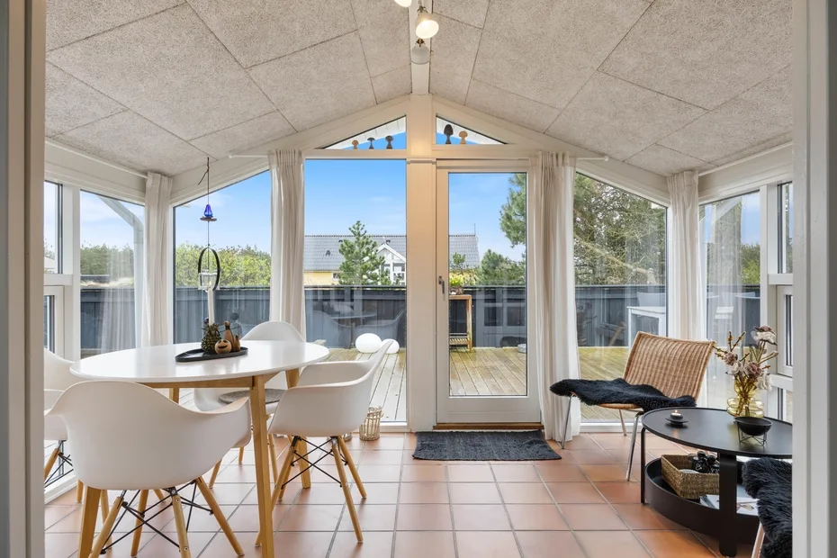 A bright dining and sitting area opens onto a deck through large windows.