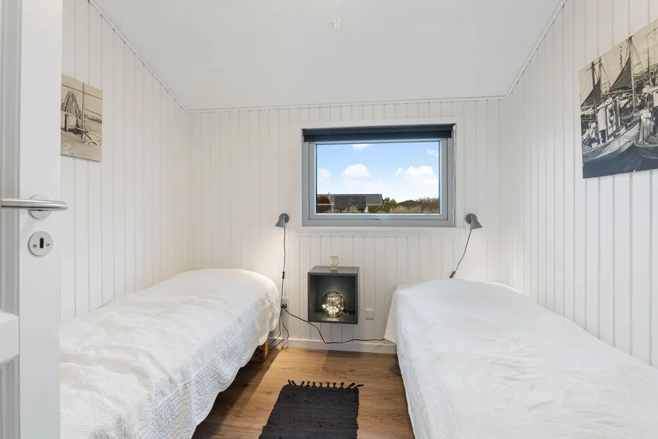 A bright twin bedroom with two beds and a window overlooking the outdoors.