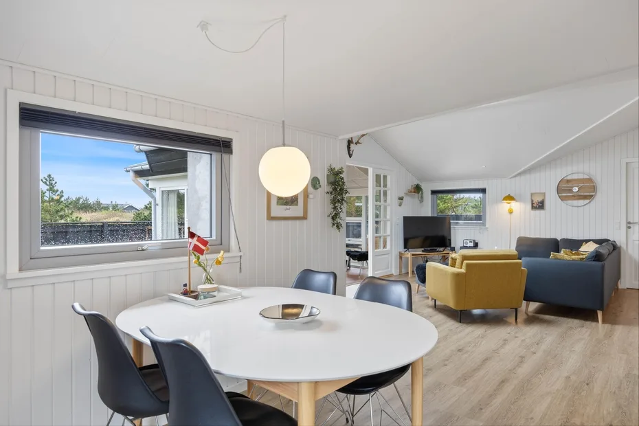 A bright open-plan dining and living area with a round table and seating.