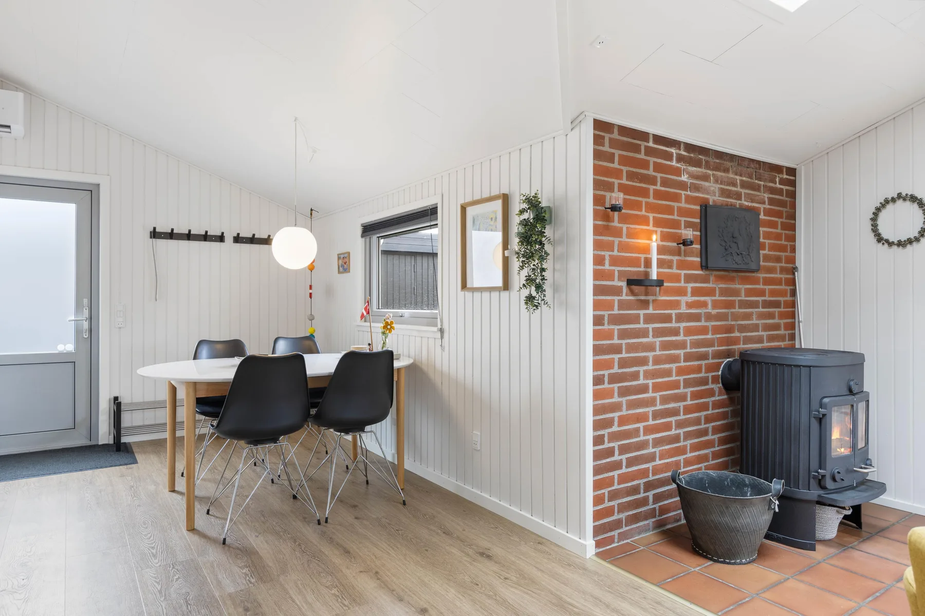 A dining area beside a brick fireplace, with a table and dark seating.