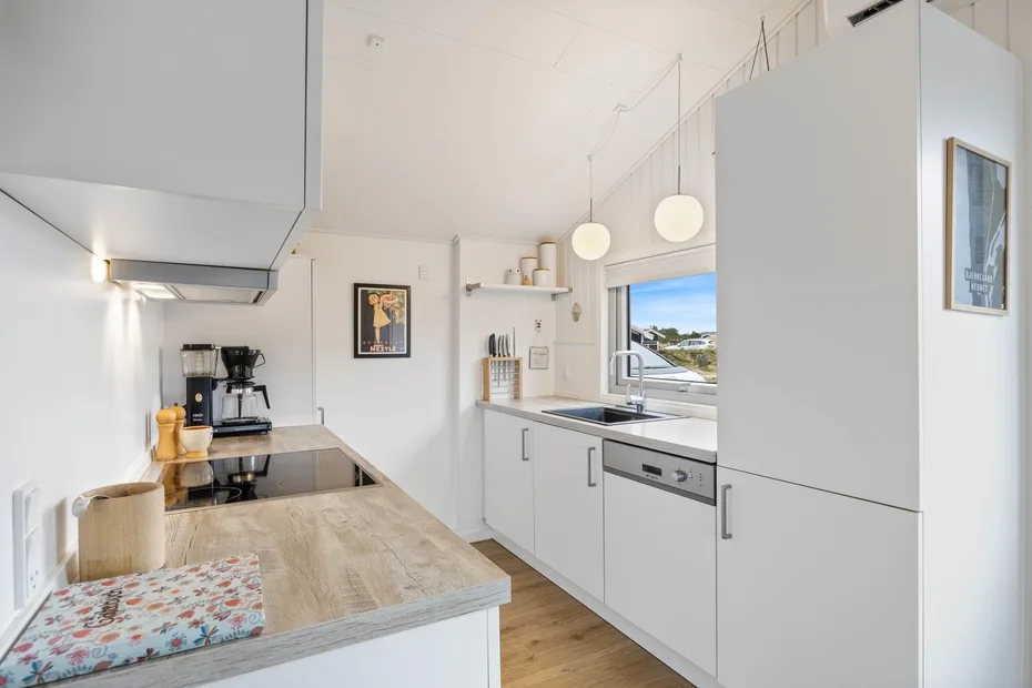A bright modern kitchen with white cabinets and a wooden countertop.