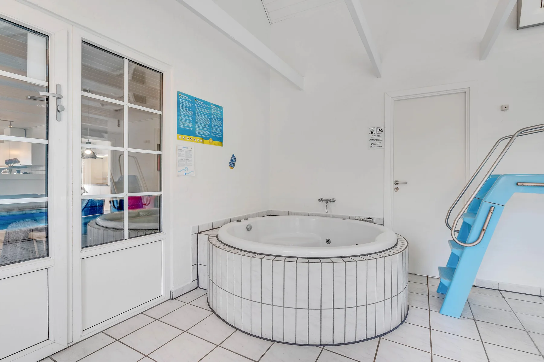 Una luminosa zona de spa interior con una gran bañera redonda y un tobogán azul.