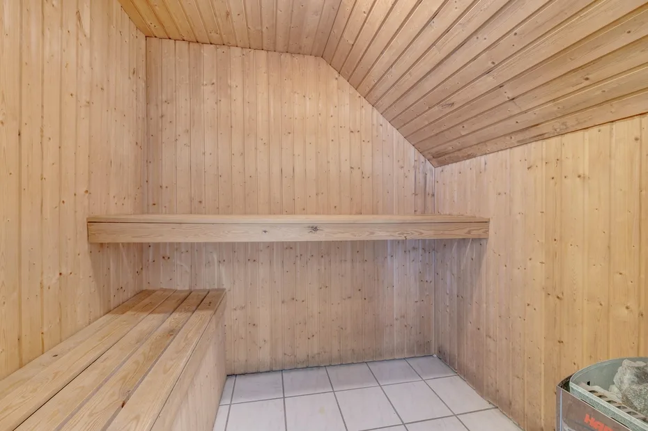 Una sauna revestida de madera, con asientos escalonados y suelo de baldosas.