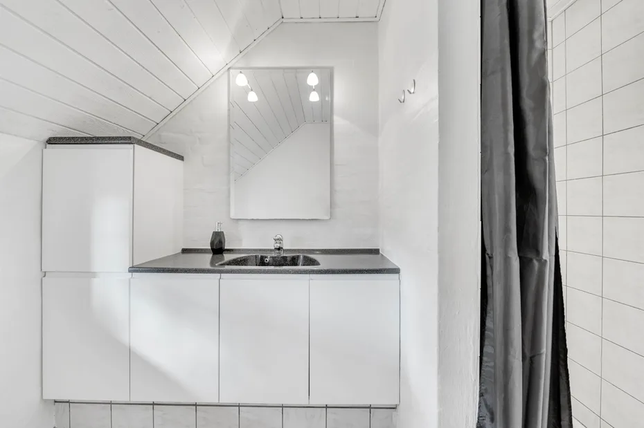 Un lavabo de baño luminoso con espejo y paredes revestidas de azulejos.