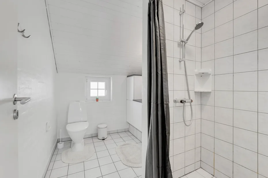 Un baño con azulejos, un inodoro y una ducha con cortina.