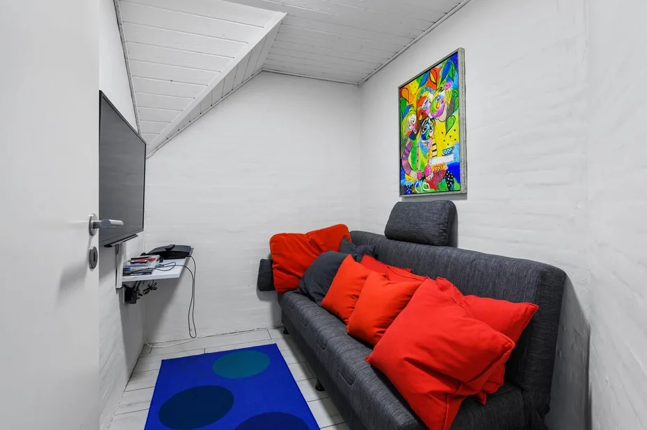 Una pequeña sala de estar con un sofá gris, cojines vivos y arte colorido en la pared.