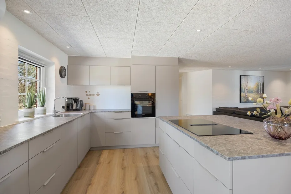 Una cocina moderna con muebles claros, un horno integrado y una isla central.