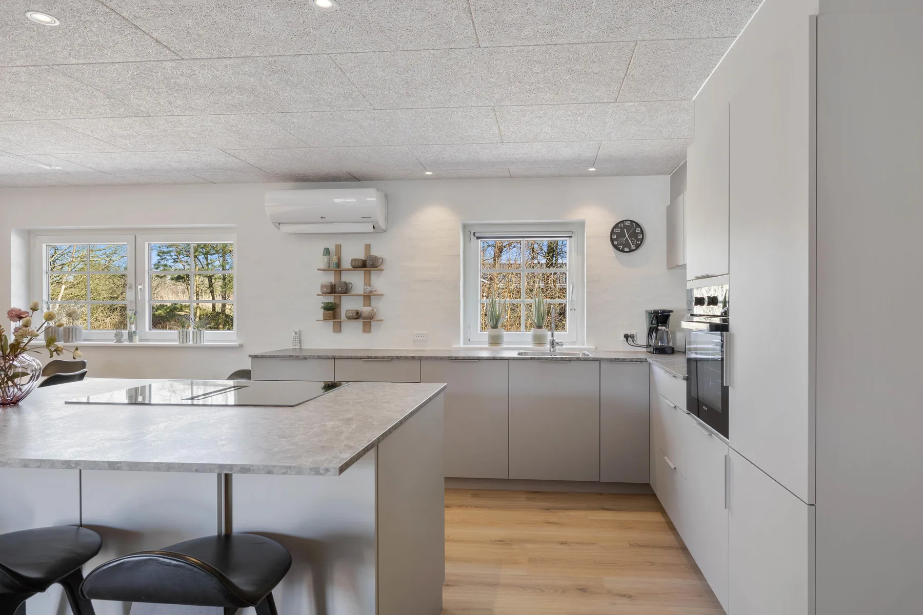 Una cocina luminosa con una isla grande y ventanas con vistas a zonas verdes.