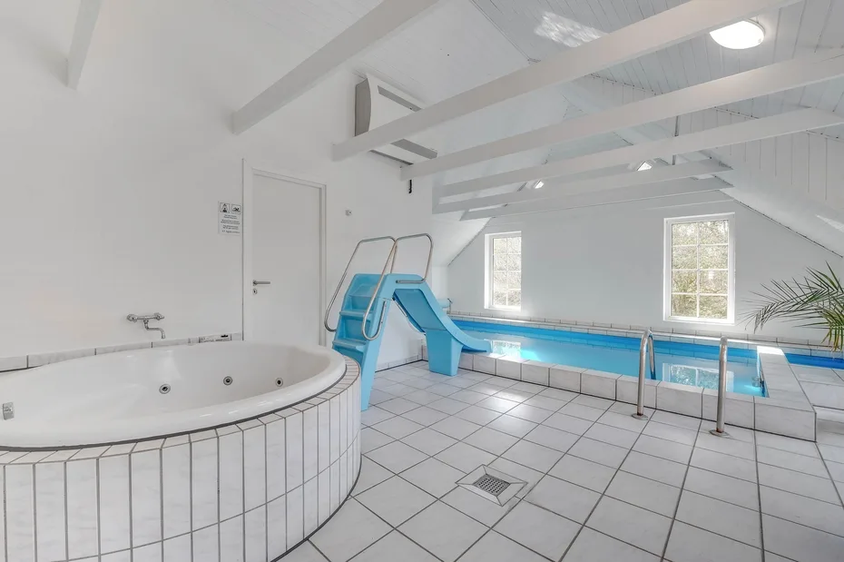 Una piscina cubierta con un tobogán azul bajo un techo inclinado.