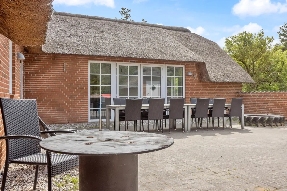 Una zona de comedor al aire libre con mesas y asientos junto a un edificio de ladrillo.