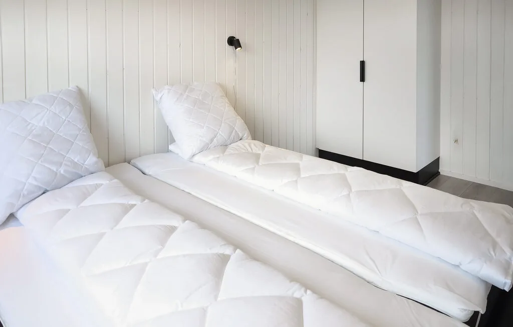 A bright bedroom with two beds dressed in white bedding.
