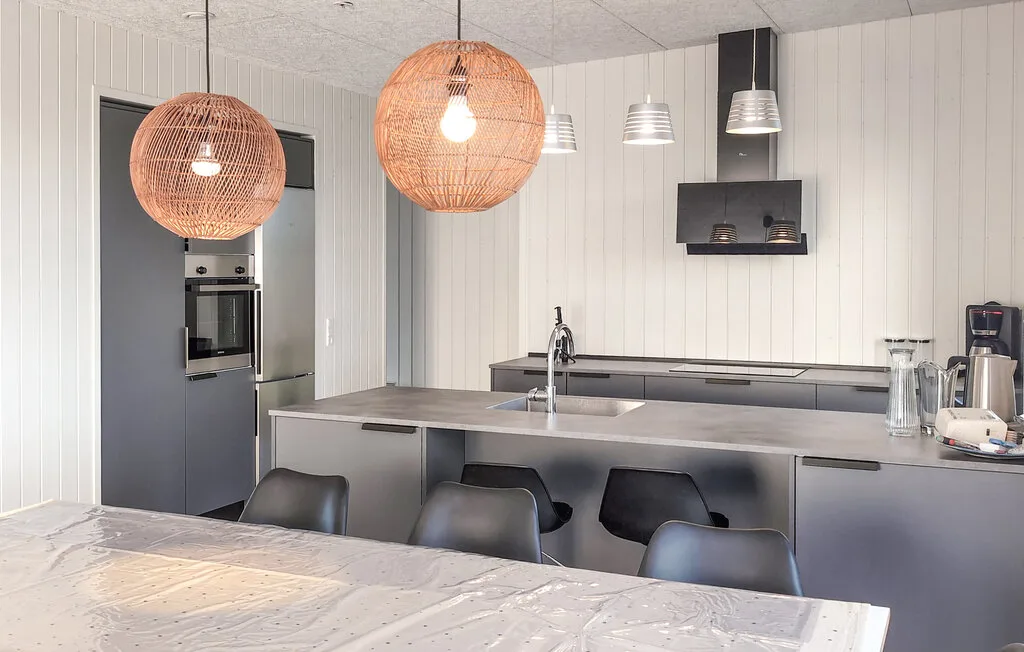 A modern kitchen with a central island and pendant lights.