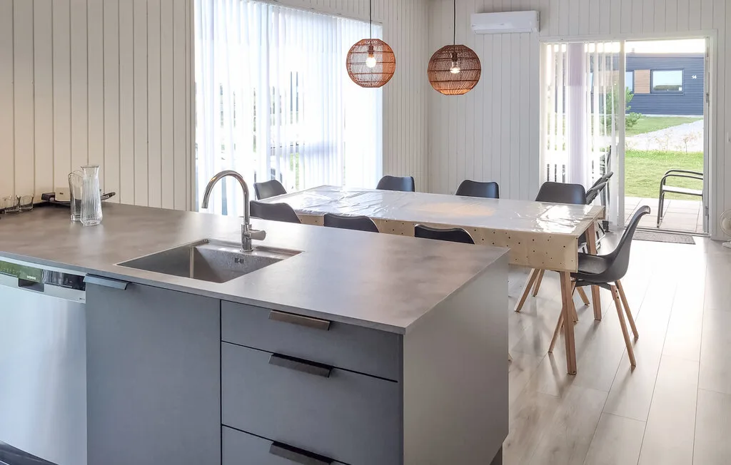 A bright dining area with a long table beside a kitchen island.