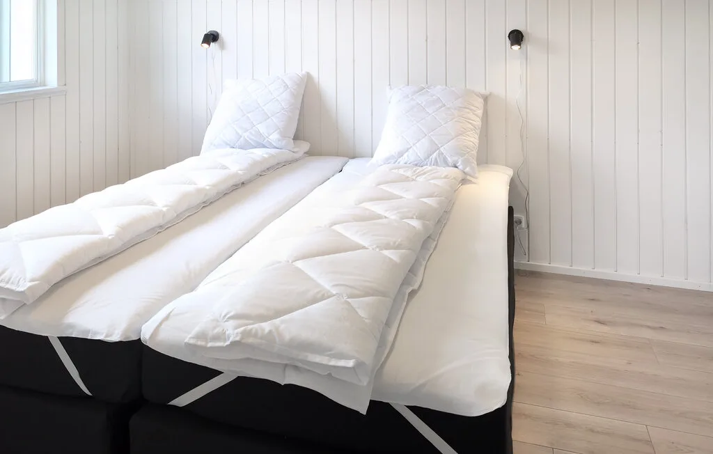 A bright bedroom with two beds dressed in white bedding.