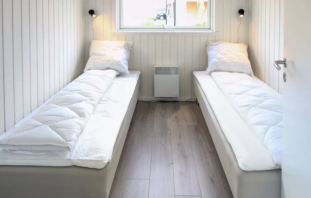 A compact bedroom with two single beds and a window.