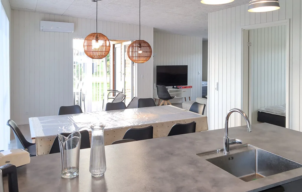 A bright open dining and kitchen area with a long table and island sink.