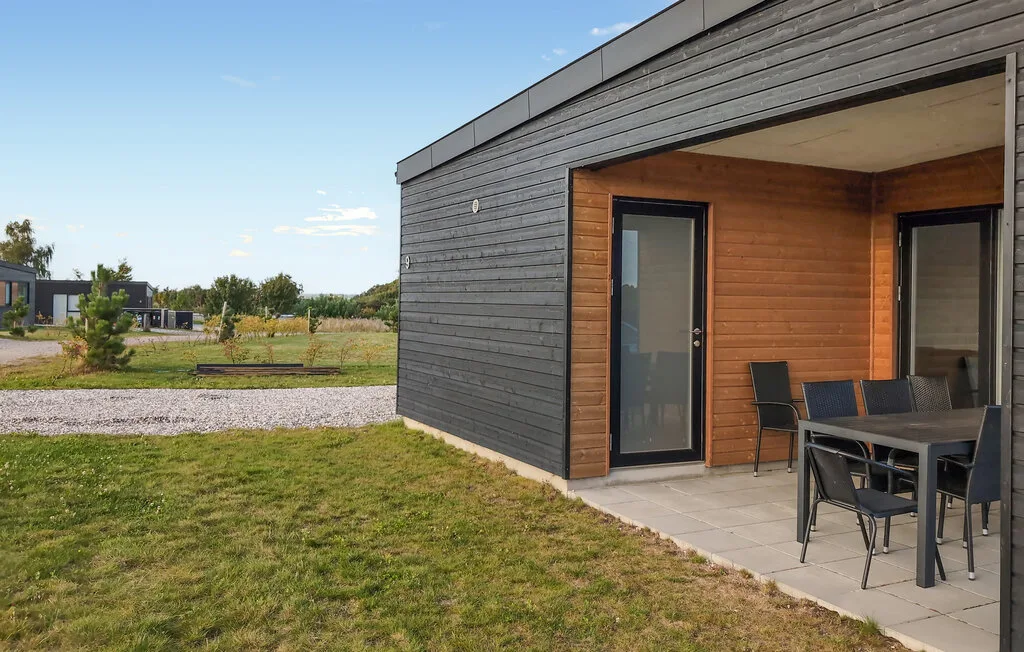 A modern cabin exterior with a covered patio and outdoor dining table.