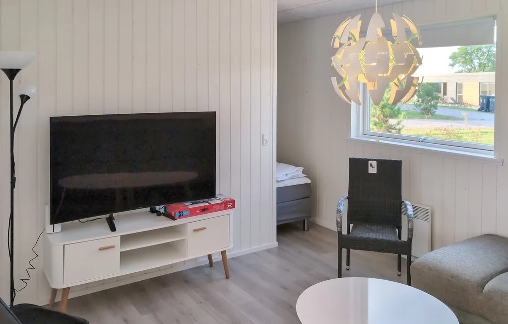 Una sala de estar con televisión, asientos y una ventana con vista a zonas verdes.