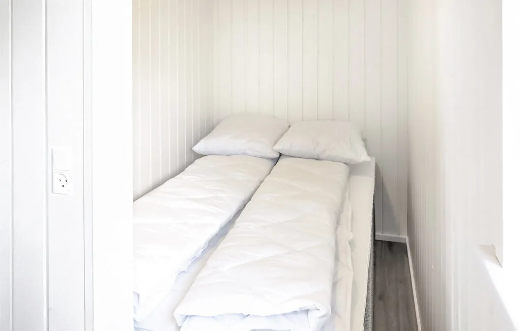 A small sleeping area with two narrow beds and white bedding.