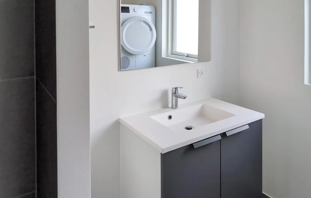 A modern bathroom with a white sink and dark vanity.