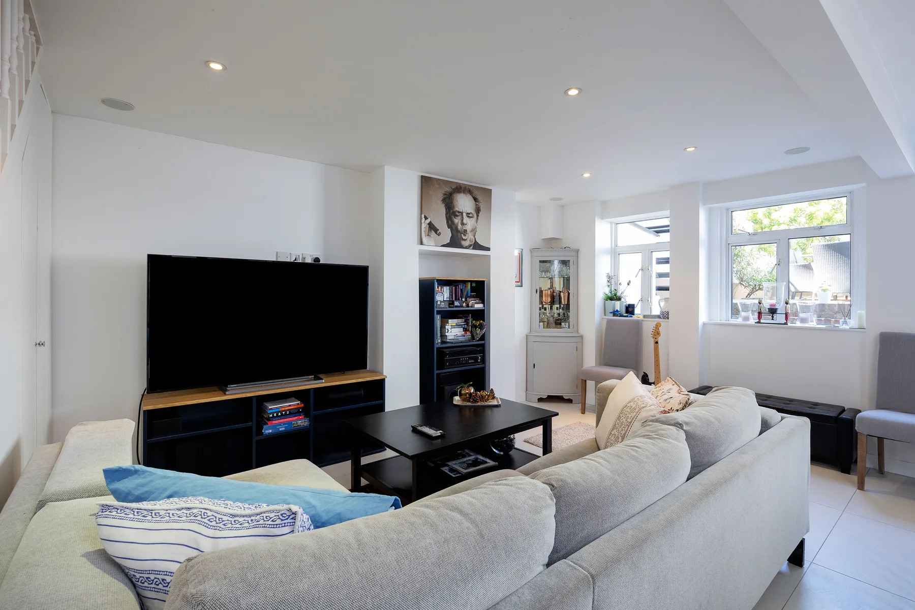 A bright living room with a television, coffee table, and light-colored seating.