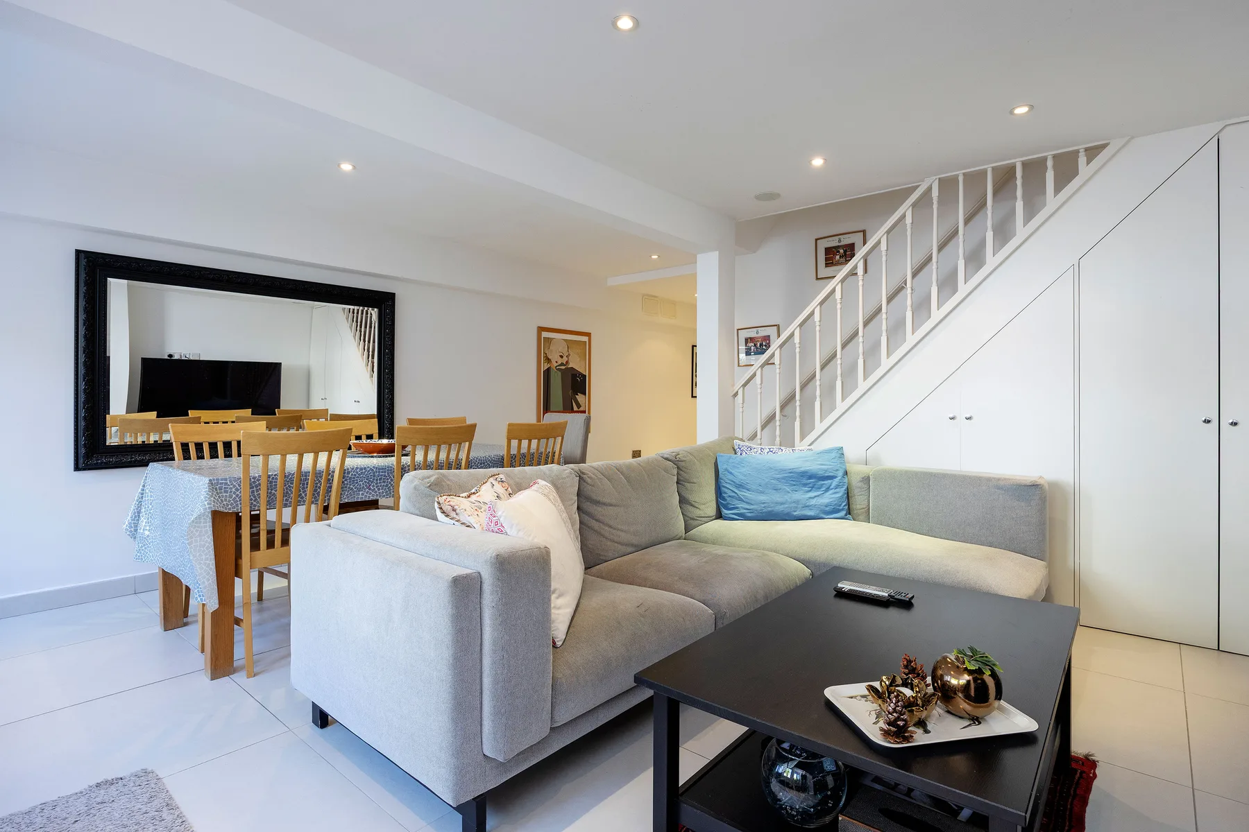 A bright living room with seating, a coffee table, and a staircase.