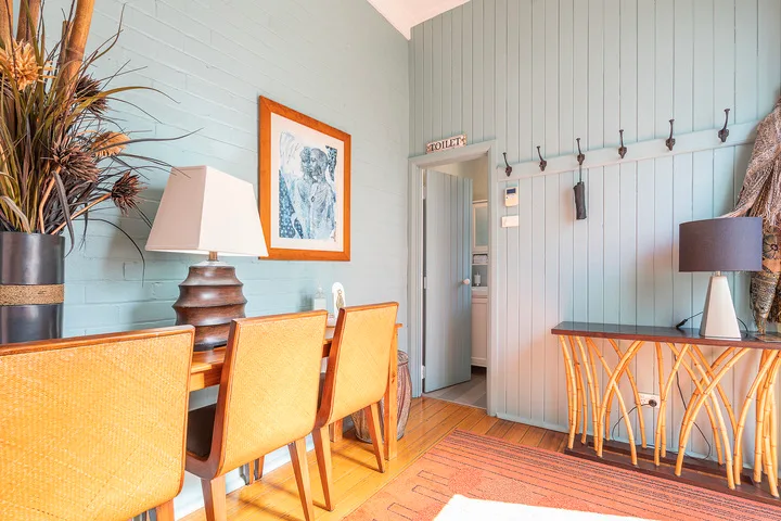 A dining area with orange seating, a table, and wall hooks.