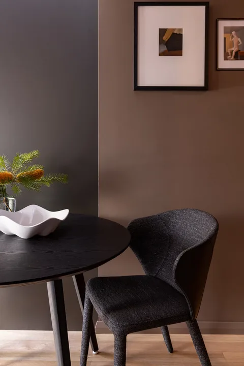 A dining nook with a dark table, upholstered seating, and framed artwork.