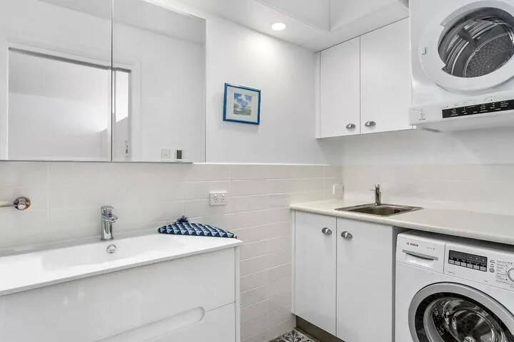 A bright bathroom with a bathtub, sink, and laundry appliances.