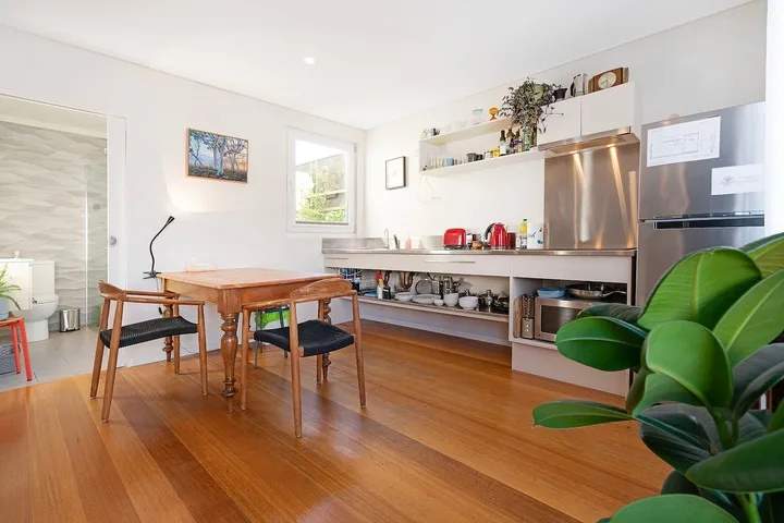 A bright kitchen and dining area with a wooden table and open shelving.
