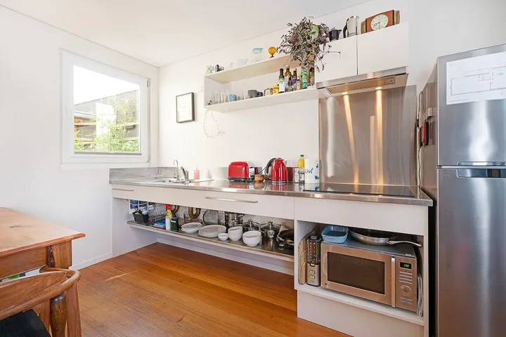 A bright kitchen with stainless steel appliances and open shelving.