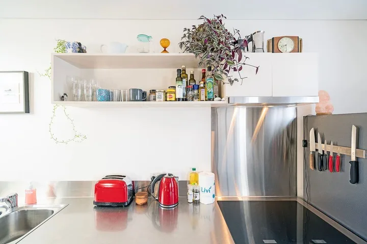 A bright kitchen with open shelves, countertop appliances, and a stainless-steel range hood.