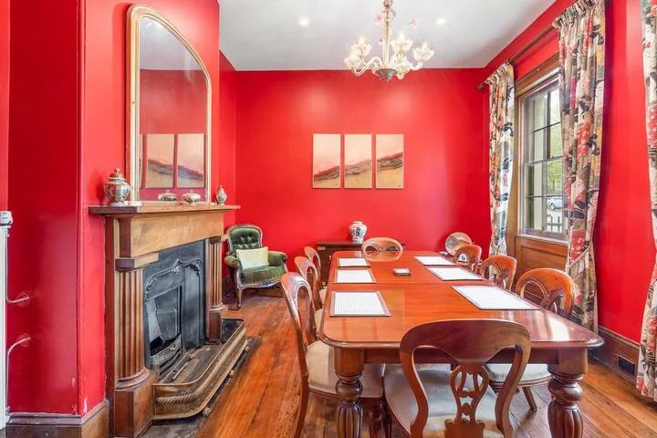 A dining room with a long wooden table and a fireplace.